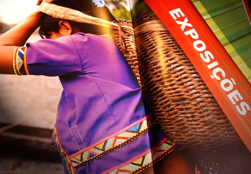Detail of the Encontro Niterói América do Sul magazine at the Exhibitions section: a woman in an embroidered purple blouse with a straw basket.